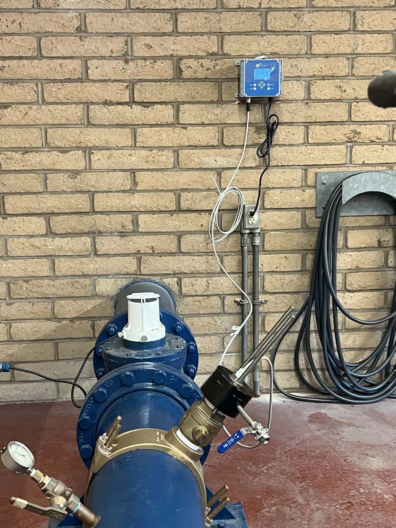 Halogen sensor installed in a blue water main, with its controller mounted on the wall above