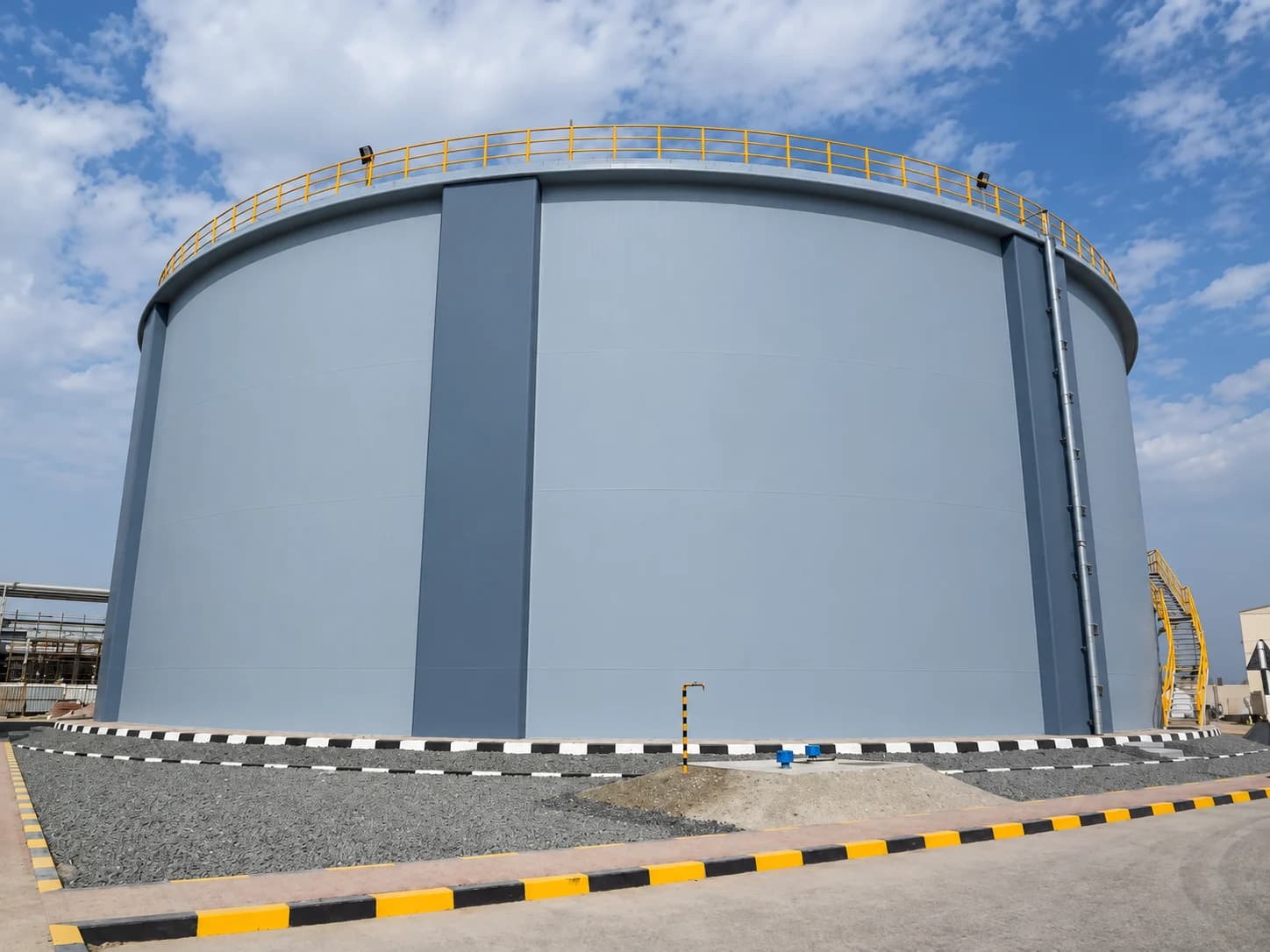 Large blue-gray cylindrical water storage tank with rooftop safety railings and an access stairway