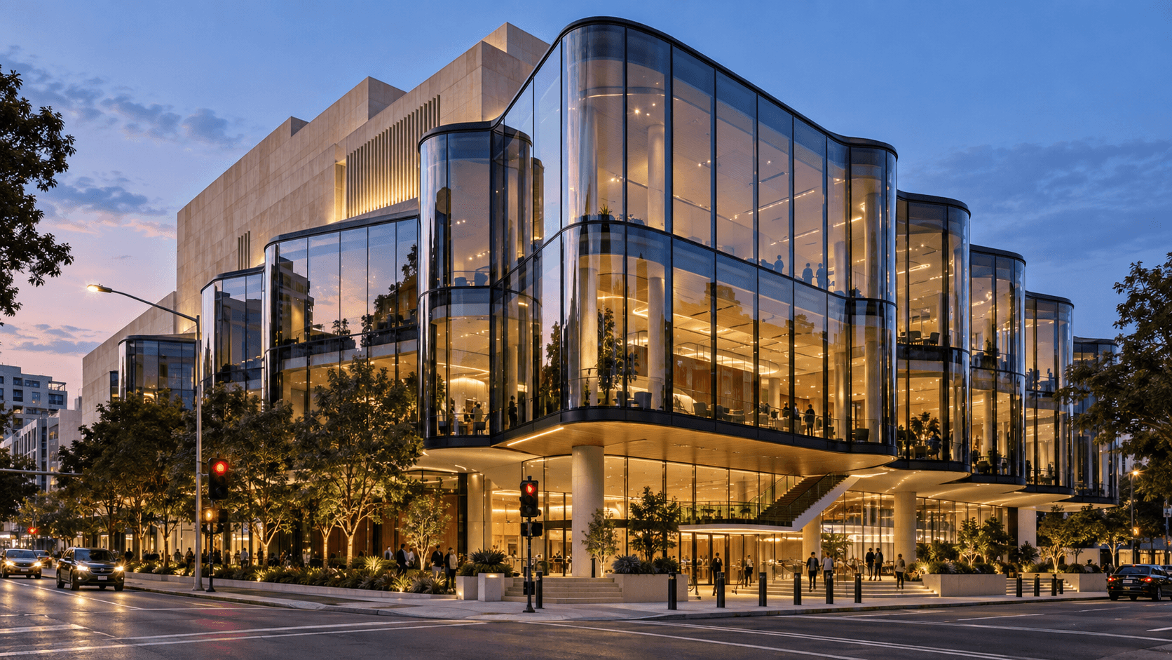 Multi-story commercial building with curved glass facades and illuminated interiors at dusk