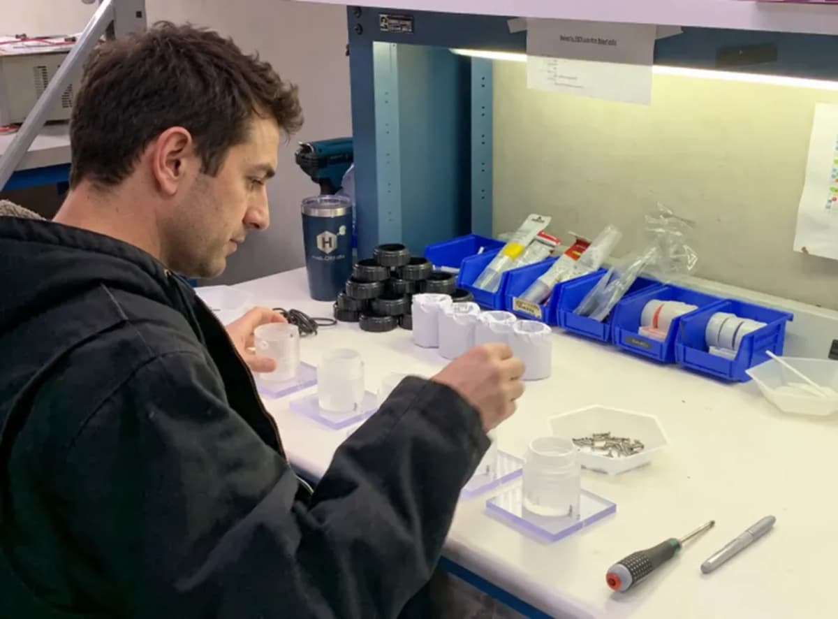 A Halogen employee assembling sensor components at a workbench