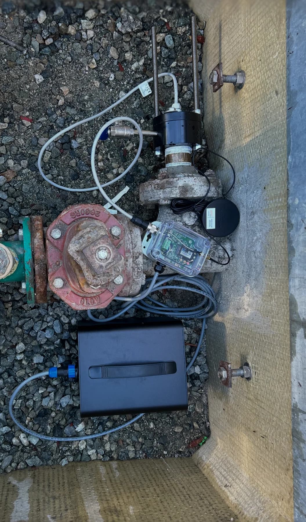 Wet-tap assembly with cabling and monitoring equipment beside piping in a vault