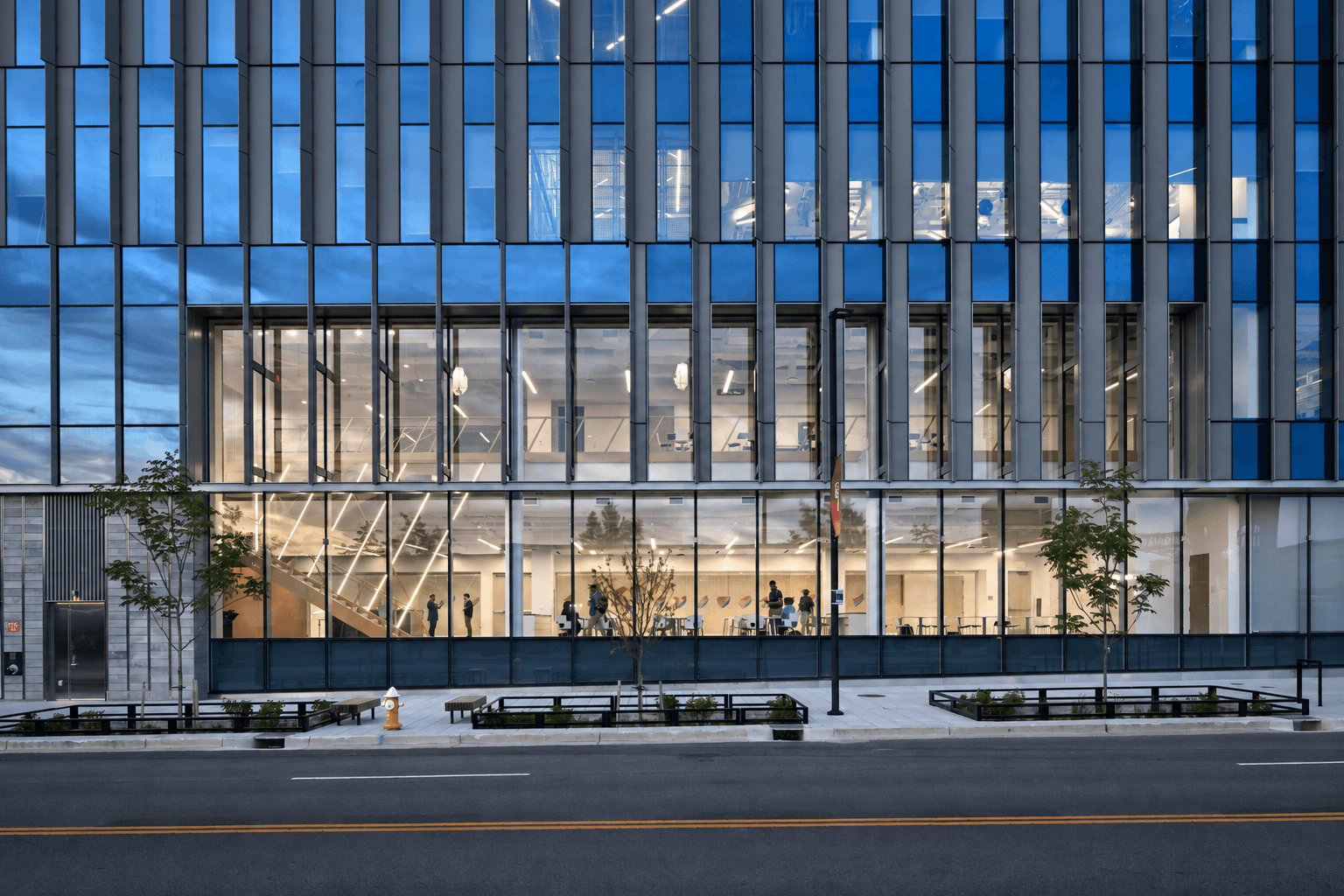 Glass-fronted commercial building with graphite facade panels and blue window reflections